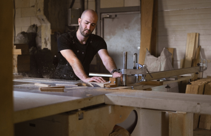 Cabinetmaker guiding a panel through workshop cutting equipment